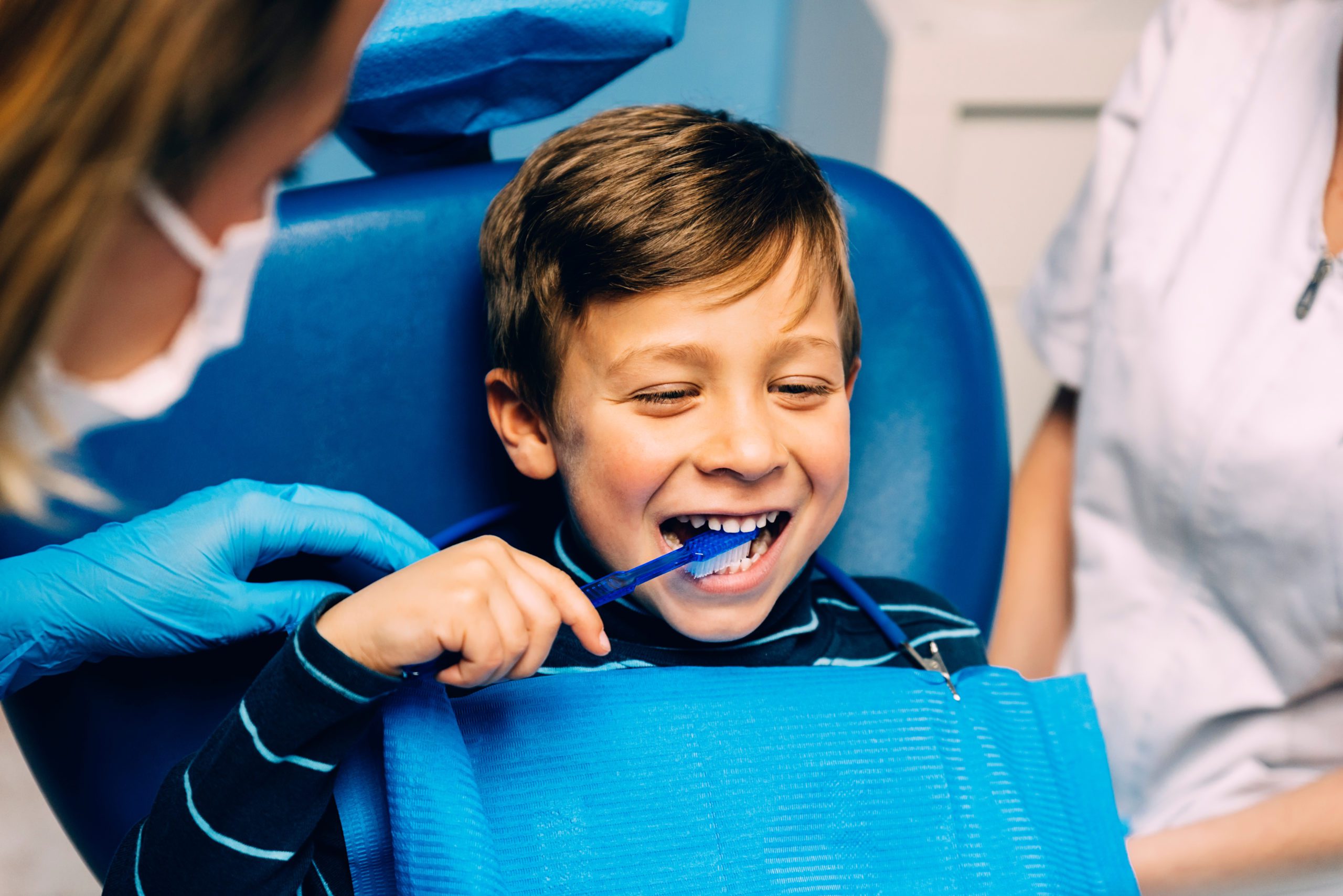 Young boy brushing his teeth at the dentist